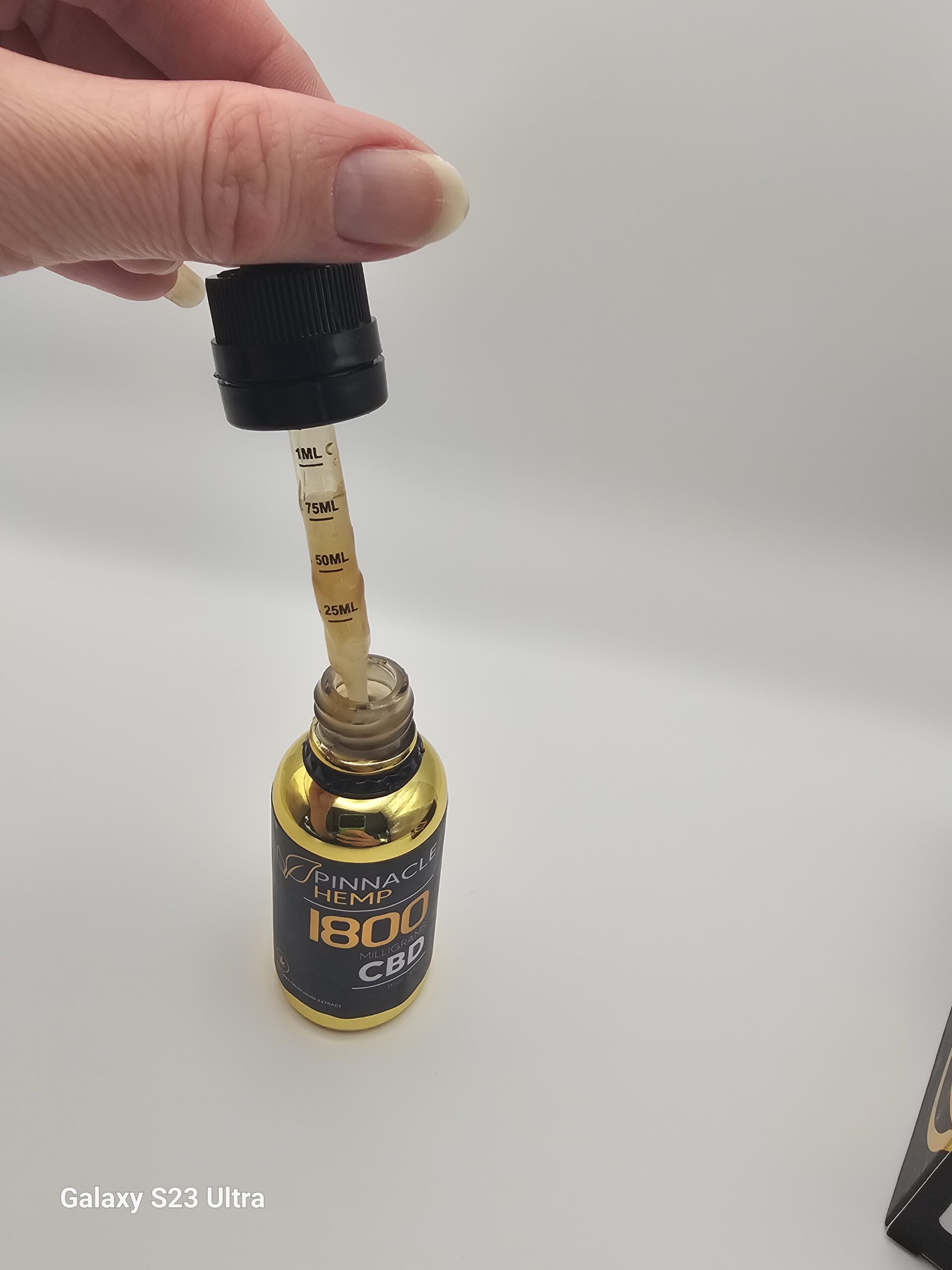 Close-up of Pinnacle Hemp CBD tincture dropper with golden full-spectrum hemp oil