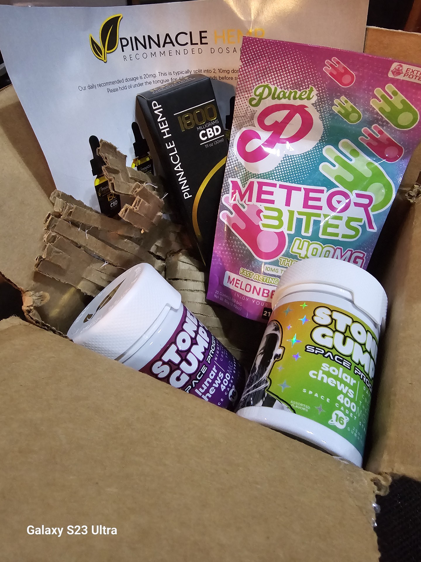 Open shipping box with Stoner Gump Solar and Lunar Chews, Pinnacle Hemp CBD tincture, and Meteorbites inside
