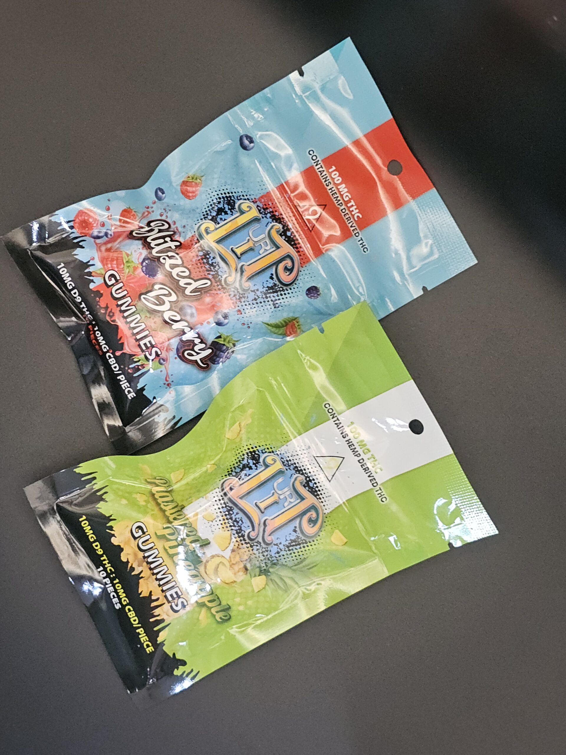 Two packages of hemp-derived THC gummies in mixed berry and pineapple flavors